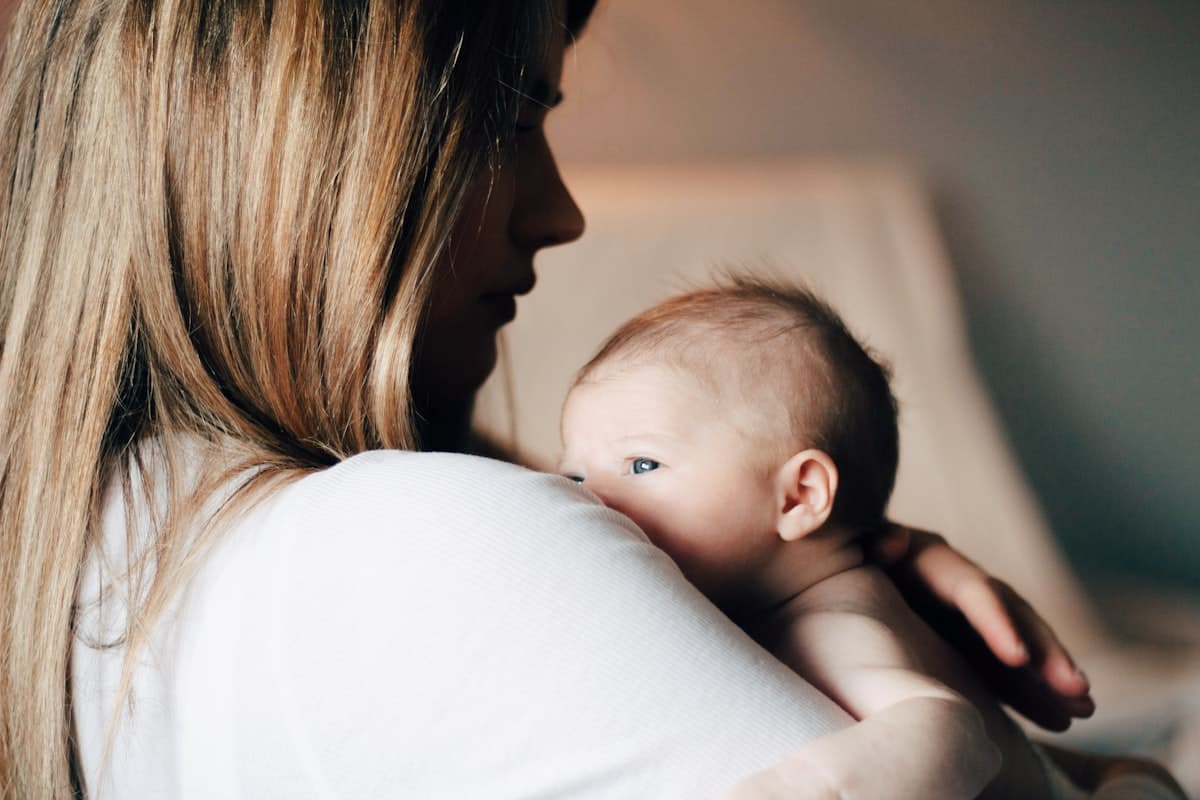 Jeune maman tenant tendrement son nouveau-né, ostéopathie du post-partum